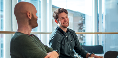 A couple of men sitting at a table with laptops.