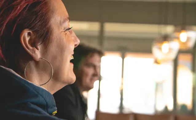A close up of a person smiling while talking to other people.