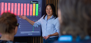 A woman at Monitor ERP giving a presentation to a group of people about Monitor BI (business intelligence)