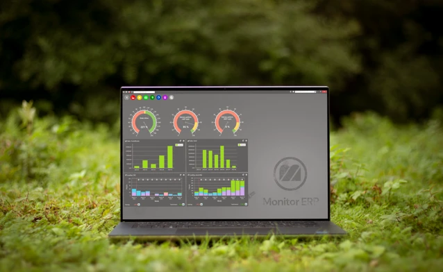Illustration av Monitor ERP:s instrumentpanel på en datorskärm, som är placerad i naturen för att symbolisera hållbarhet.