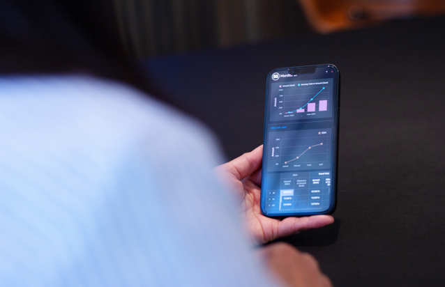 A person holding a cell phone in their hand displaying Monitor ERP 