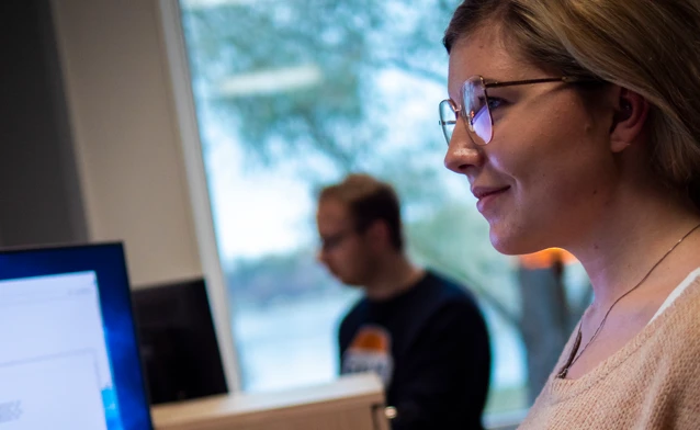 En kvinna med glasögon som tittar på en datorskärm.