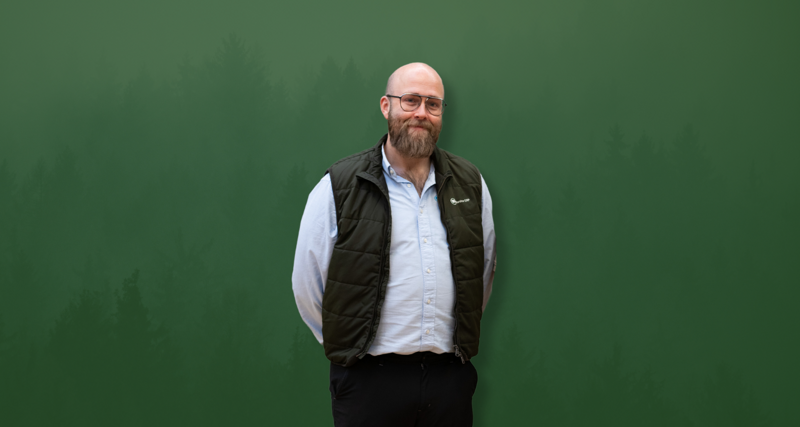 David Mariasdotter, Sustainability consultant at Monitor ERP, standing with hands behind back in front of green background