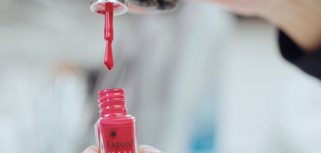 A woman is holding a bottle of nail polish.
