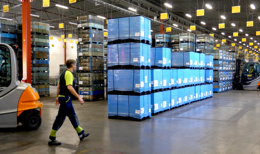 A man walking through a warehouse filled with boxes.