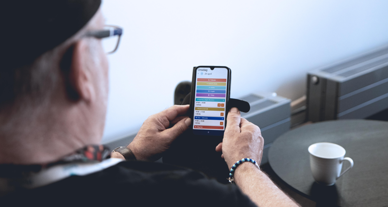 Person sitter med mobil och använder Monitor ERP tidkort.