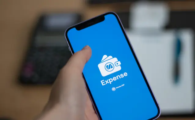 A person holding a cell phone with a Monitor Expense logo.