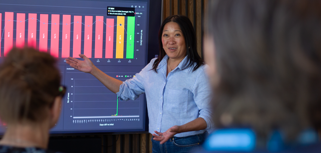 A woman at Monitor ERP giving a presentation to a group of people about Monitor BI (business intelligence)