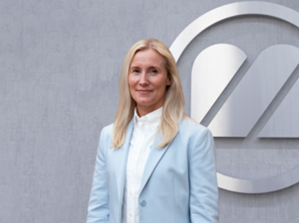 A woman standing in front of a logo.