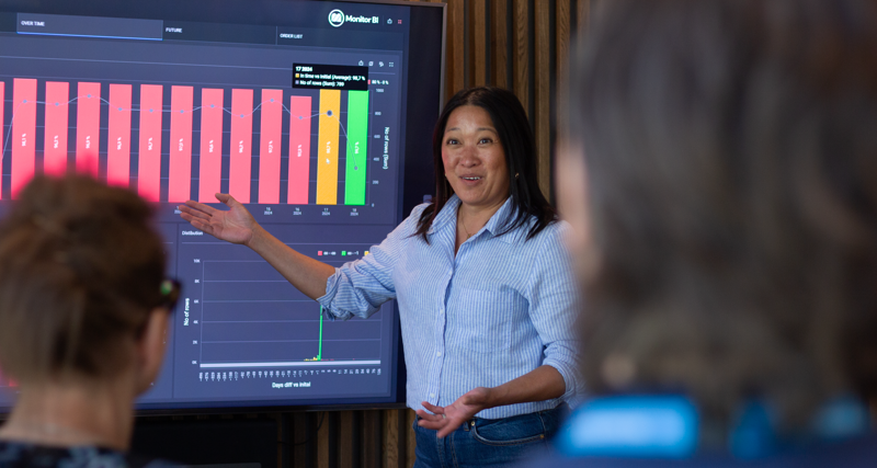 A woman at Monitor ERP giving a presentation to a group of people about Monitor BI (business intelligence)