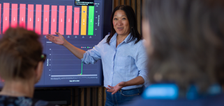 A woman at Monitor ERP giving a presentation to a group of people about Monitor BI (business intelligence)