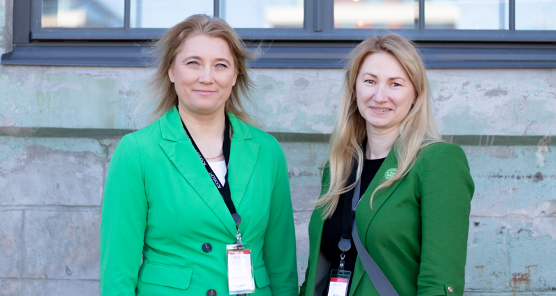 Two women standing next to each other dressed in green