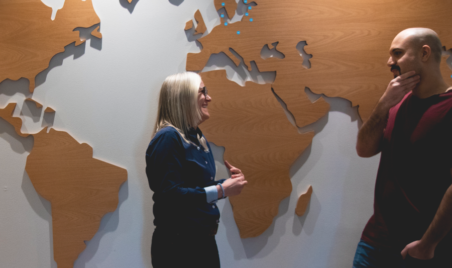 Två anställda på Monitor står framför en världskarta. 