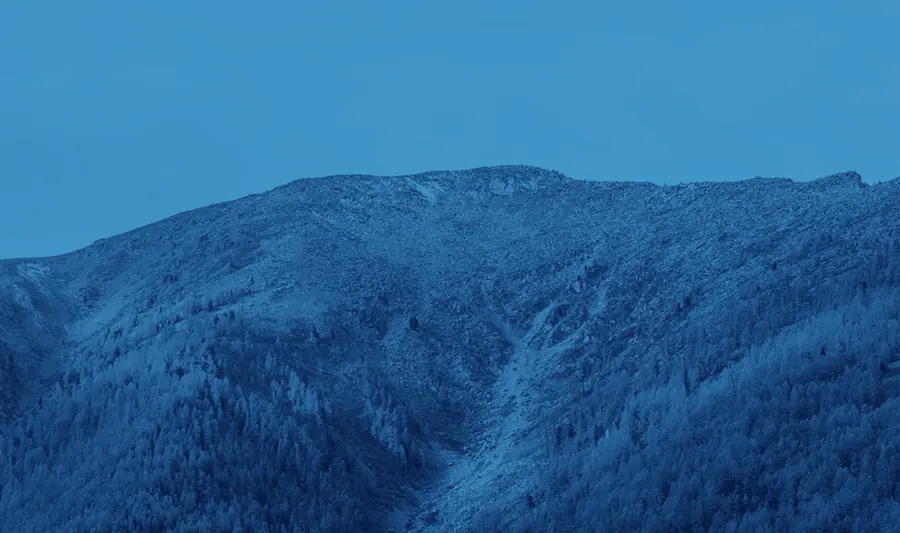 Ett högt, snötäckt berg under en blå himmel.