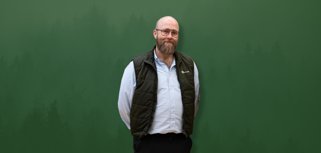 David Mariasdotter, Sustainability consultant at Monitor ERP, standing with hands behind back in front of green background