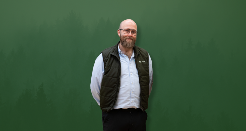 David Mariasdotter, Sustainability consultant at Monitor ERP, standing with hands behind back in front of green background