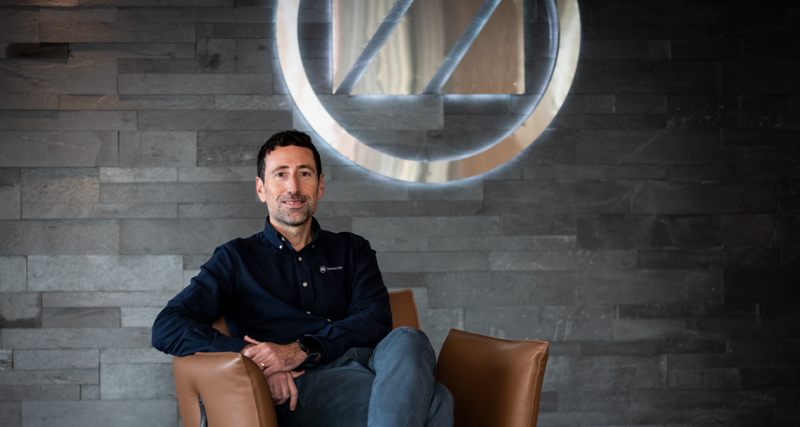 Adrian Aptowitzer, VD för Monitor ERP Sverige, sitter i en fåtölj framför en skylt med Monitor-loggan. 