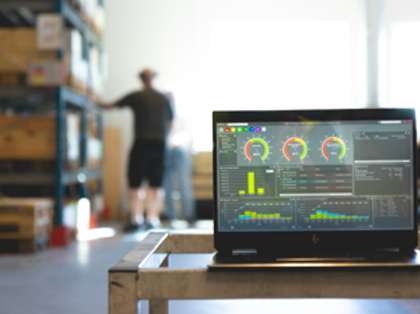 Monitor ERP dashboard som visas på en laptop ståendes på ett bord  i en fabriksmiljö.
