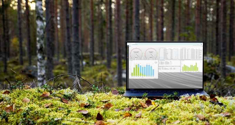 A laptop computer displaying Monitor ERP sitting on top of a moss covered ground surrounded by trees.