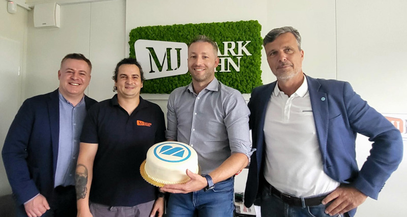A group of men standing next to each other holding a cake.