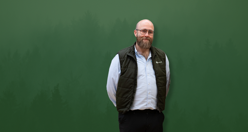 David Mariasdotter, Sustainability consultant at Monitor ERP, standing with hands behind back in front of green background