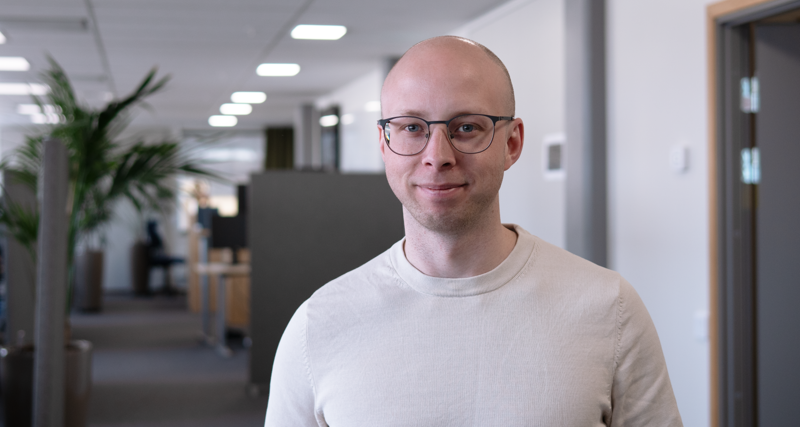 Jonas Lundin står i ett kontorslandskap och tittar in i kameran. 