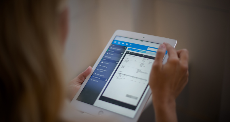 A woman is holding a tablet displaying a digital invoice. 
