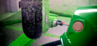 A close up of a green machine with a hose connected to it.