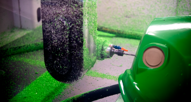 A close up of a green machine with a hose connected to it.