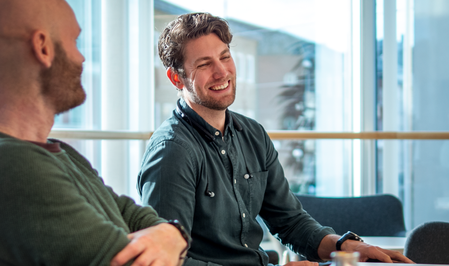 A couple of men sitting at a table with laptops.