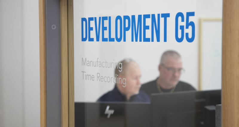 Kenneth och Thomas står och arbetar vid en dator.