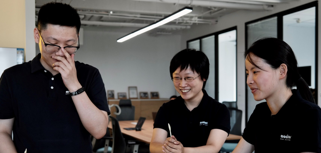 Tre medarbetare på Monitor i Kina står och pratar med varandra.