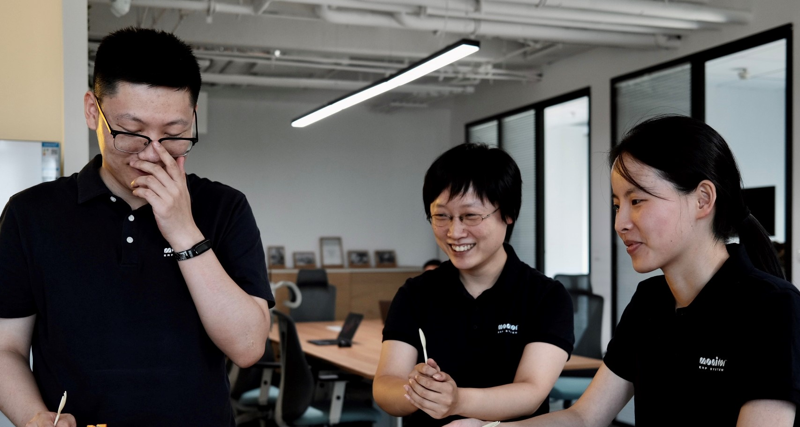 Tre medarbetare på Monitor i Kina står och pratar med varandra.