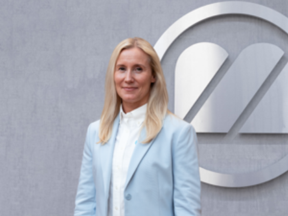 A woman standing in front of a logo.