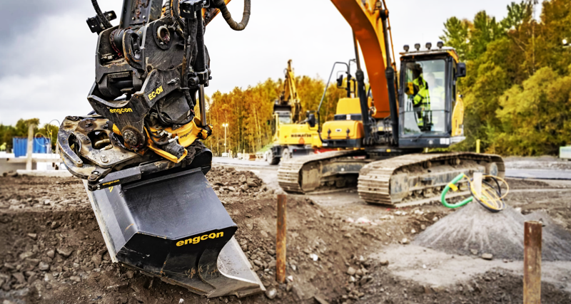 A construction site with an engcon tilt rotator and excavator in the background.