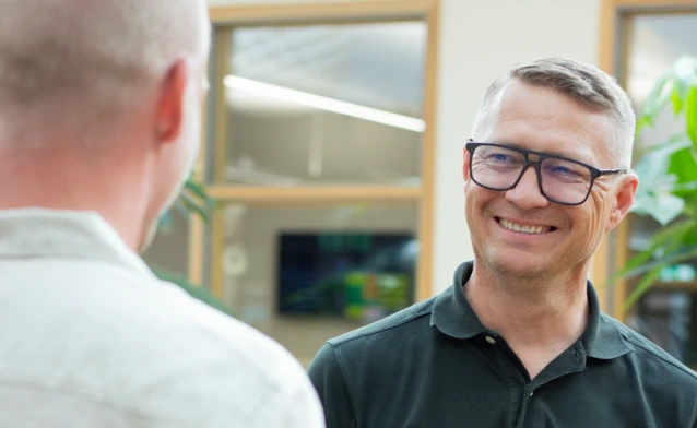 A man standing next to another man at a table looking happy at Monitor ERP HQ.