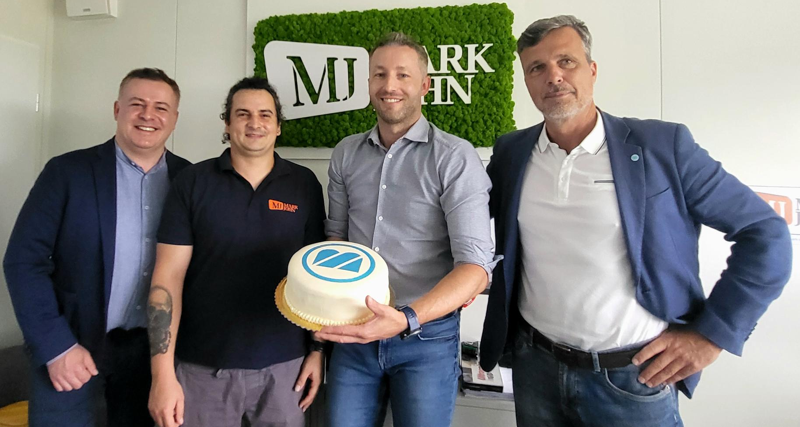 A group of men standing next to each other holding a cake.