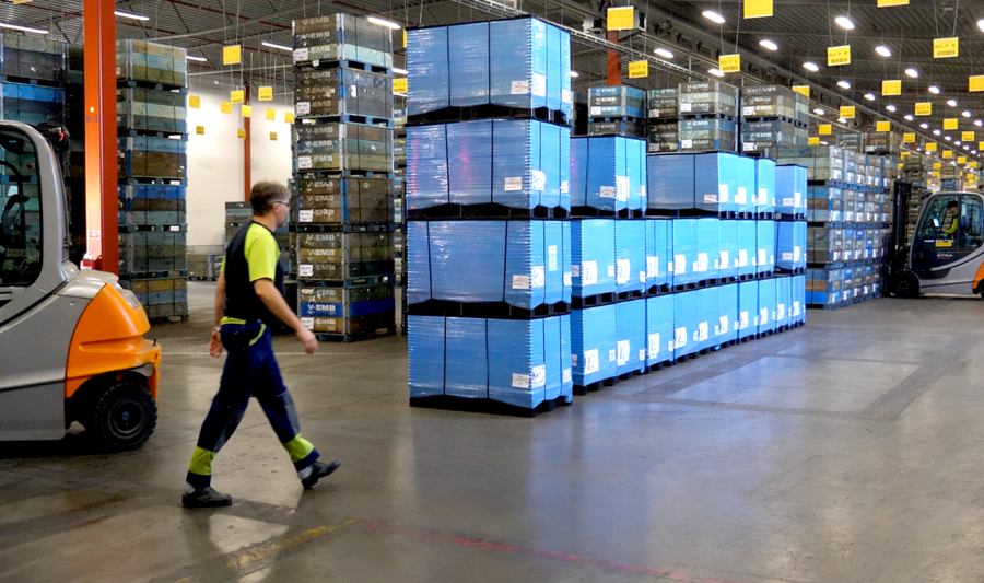 A man walking through a warehouse filled with boxes.