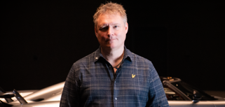 Mikael Melander, Senior ERP System Specialist at Koenigsegg Automotive standing in front of a Koenigsegg sports car.