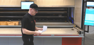 A man in a black shirt is walking by a machine.