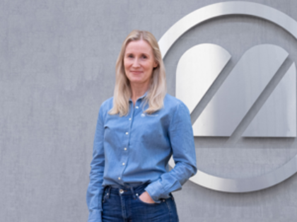 A woman standing in front of a logo.
