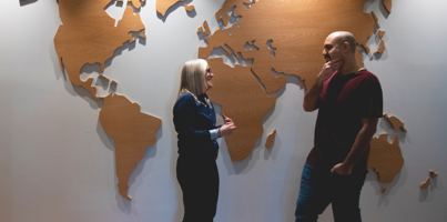 Two people standing in front of a world map