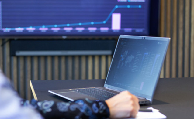 Laptop z uruchomionym systemem Monitor ERP, w tle ekran z danymi z Monitor BI.