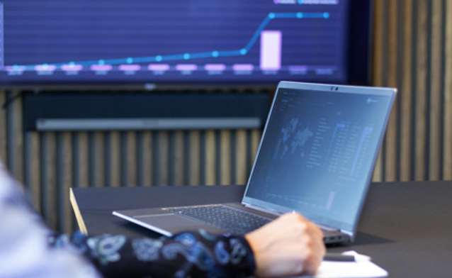Laptop z uruchomionym systemem Monitor ERP, w tle ekran z danymi z Monitor BI.