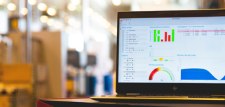 Monitor ERP dashboard displayed on a laptop in a factory environment.