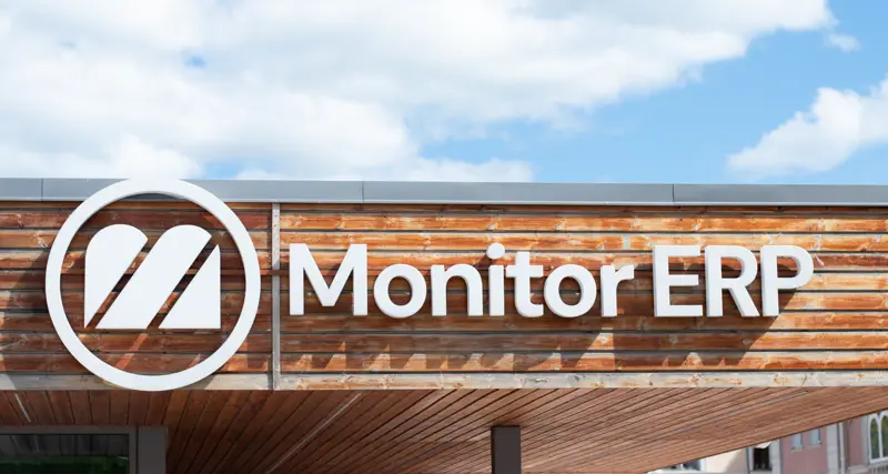 Logotyp Monitora ERP na budynku firmowym, w tle błękitne niebo.