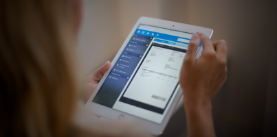 A woman is holding a tablet displaying a digital invoice. 