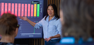 A woman at Monitor ERP giving a presentation to a group of people about Monitor BI (business intelligence)