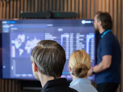Mężczyzna przeprowadzający prezentację systemu Monitor ERP i Monitor BI na dużym ekranie - ludzie wpatrują się w niego.
