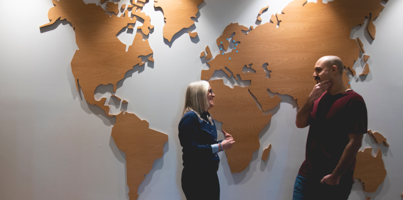 Two people standing in front of a world map